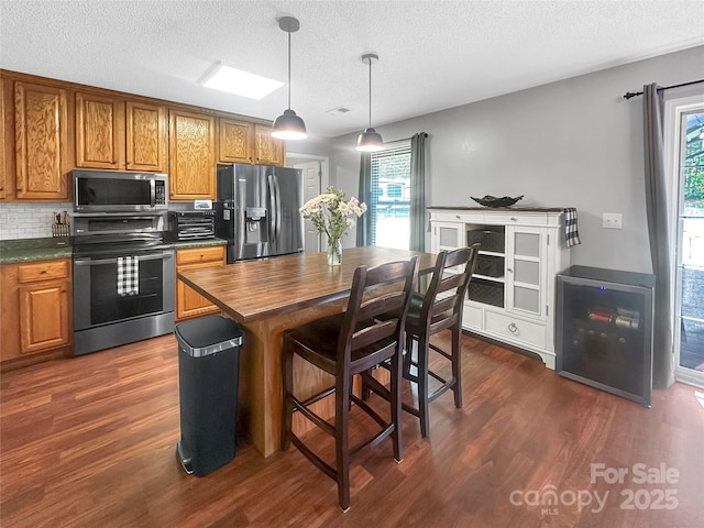 118 Harvey Vale Cir, Blacksburg, SC 29702 - kitchen with stainless steel appliances, dark wood-style floors, brown cabinetry, a textured ceiling, and pendant lighting