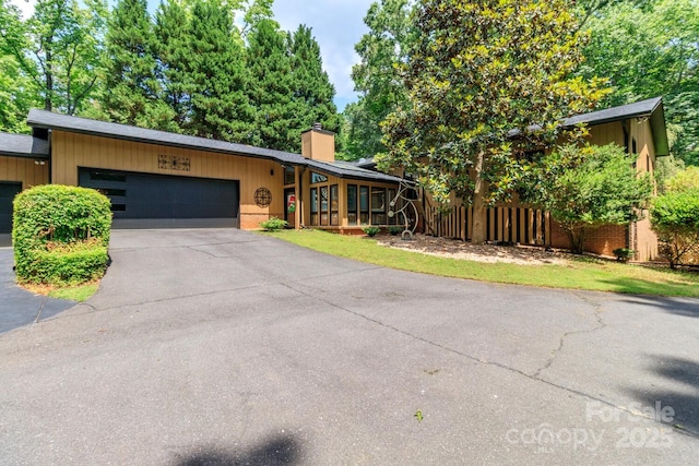 6119 Bittersweet Ln, Charlotte, NC 28270 - mid-century modern home featuring fence, a chimney, an attached garage, driveway, and brick siding
