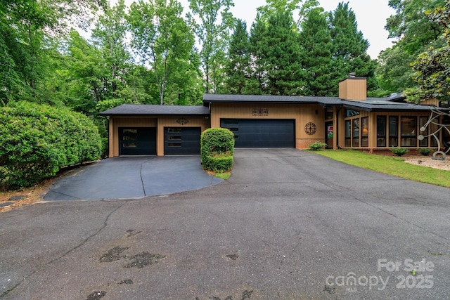 6119 Bittersweet Ln, Charlotte, NC 28270 - mid-century modern home featuring driveway, an attached garage, a chimney, and view of wooded area