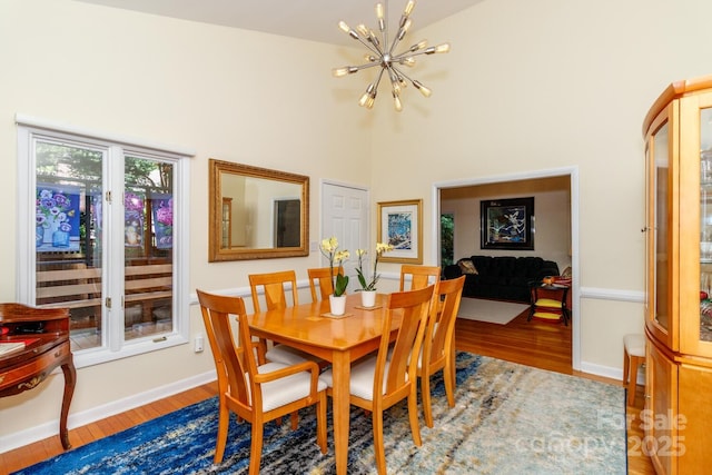6119 Bittersweet Ln, Charlotte, NC 28270 - dining area with a chandelier, a towering ceiling, wood finished floors, and baseboards
