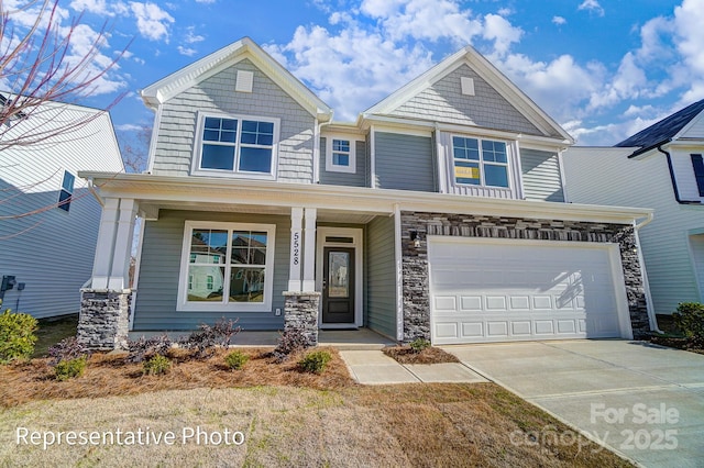 craftsman-style home featuring covered porch, driveway, a garage, and stone siding