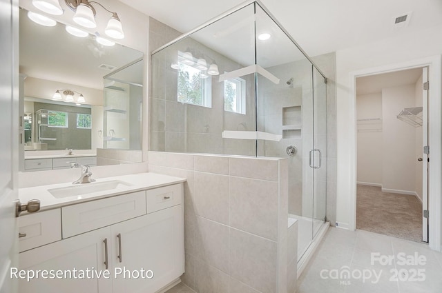 bathroom with tile patterned floors, a stall shower, vanity, and a walk in closet