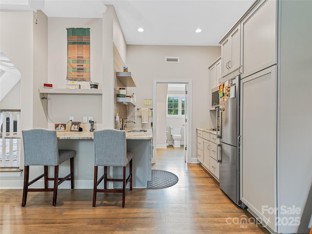63 Chantilly Dr, Asheville, NC 28804 - kitchen with open shelves, a breakfast bar, light wood finished floors, light countertops, and a sink