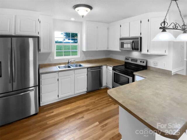 7308 Pleasant Hill Church Rd, Marshville, NC 28103 - kitchen with appliances with stainless steel finishes, a sink, light wood-type flooring, white cabinets, and a peninsula