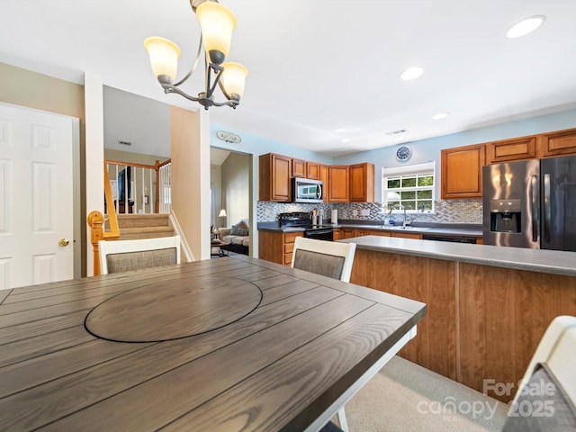 3446 Broadwick St, Charlotte, NC 28213 - kitchen with appliances with stainless steel finishes, brown cabinets, decorative backsplash, a chandelier, and recessed lighting