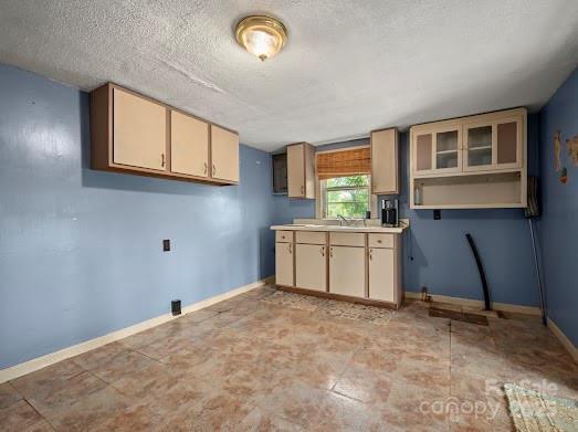 751 Ted Smith Rd, Rutherfordton, NC 28139 - kitchen with a textured ceiling, baseboards, a sink, light countertops, and cream cabinetry