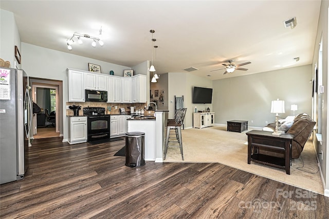 4018 Harmattan Dr, Denver, NC 28037 - kitchen with black appliances, open floor plan, dark wood finished floors, dark countertops, and a kitchen breakfast bar