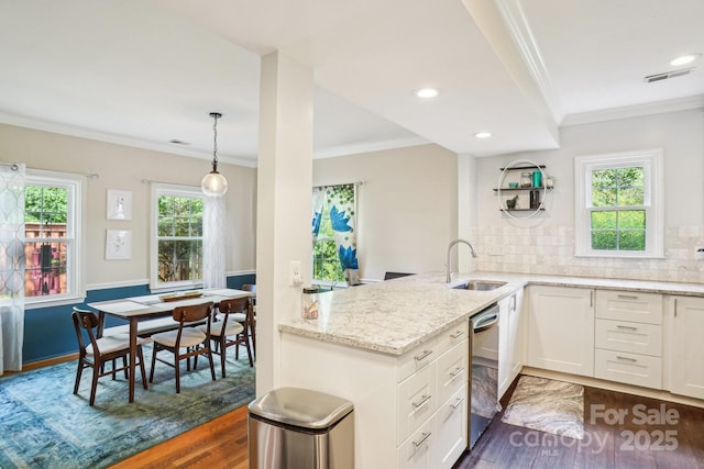 kitchen featuring a sink, dishwasher, crown molding, dark wood-style floors, and a peninsula
