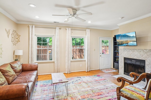 living room featuring a ceiling fan, wood finished floors, a fireplace, ornamental molding, and recessed lighting