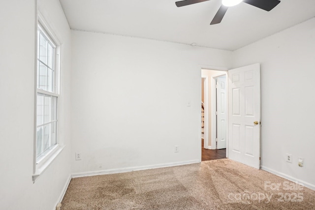 carpeted empty room featuring a ceiling fan, healthy amount of natural light, and baseboards