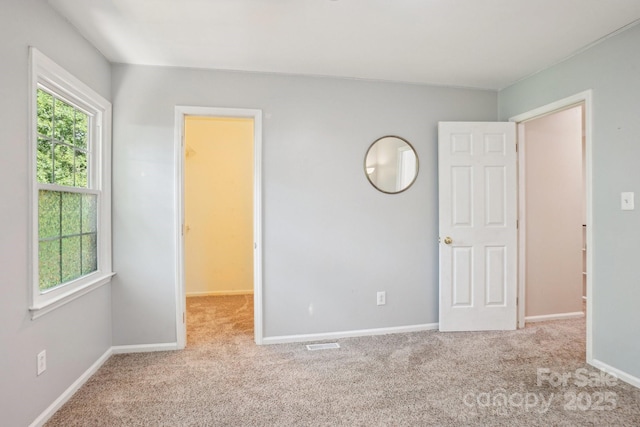 unfurnished bedroom with carpet floors, baseboards, and a spacious closet