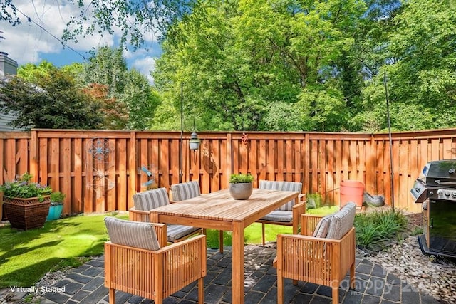 view of patio featuring area for grilling, a fenced backyard, and outdoor dining area