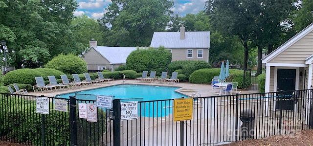 community pool featuring fence, a patio area, and view of scattered trees
