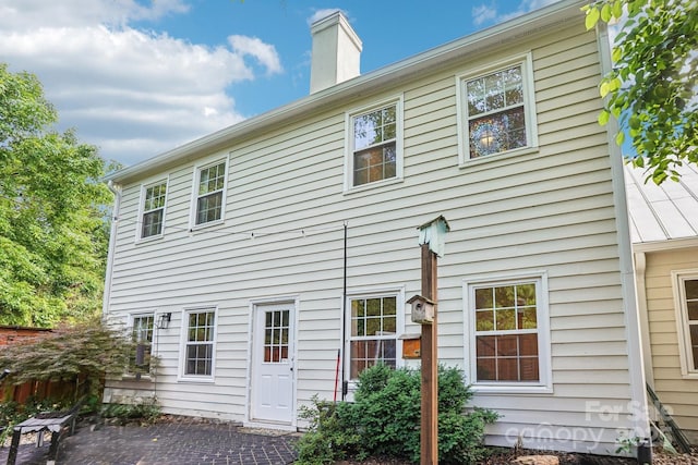 back of property with a chimney and a patio area