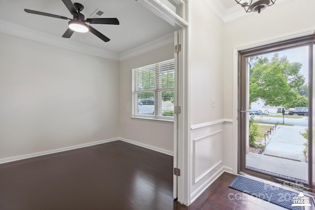 foyer entrance with ornamental molding, dark wood-style flooring, a ceiling fan, and a wainscoted wall