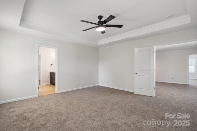 empty room featuring a tray ceiling, crown molding, carpet floors, ceiling fan, and baseboards
