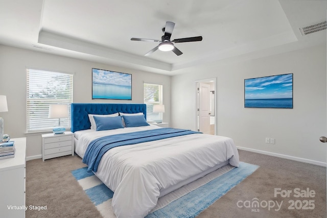 bedroom featuring a raised ceiling, light colored carpet, baseboards, and ornamental molding