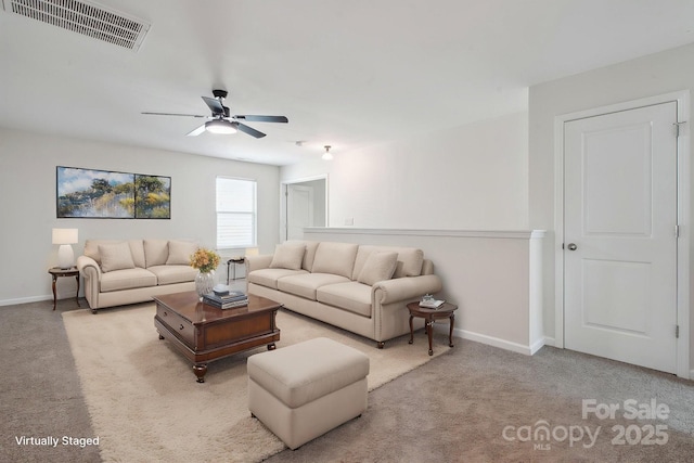 carpeted living area with ceiling fan and baseboards