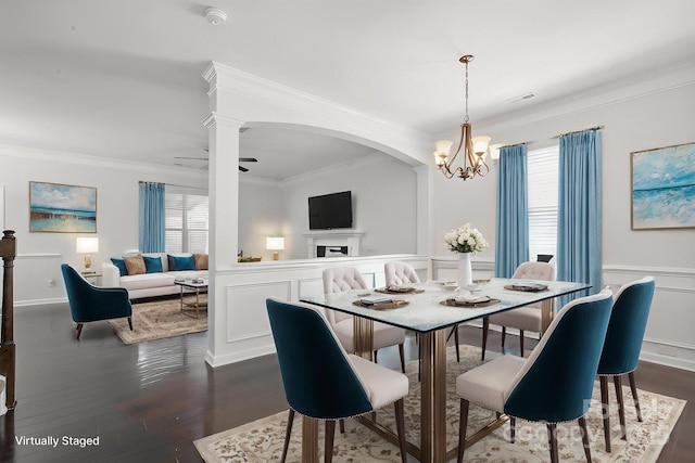 dining space with crown molding, a decorative wall, a chandelier, wainscoting, and dark wood-style flooring