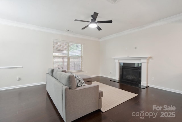 living room featuring crown molding, ceiling fan, baseboards, a glass covered fireplace, and dark wood finished floors