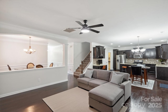 392 Winecoff Woods Dr NW, Concord, NC 28027 - living room with a chandelier, a ceiling fan, ornamental molding, dark wood-style flooring, and arched walkways
