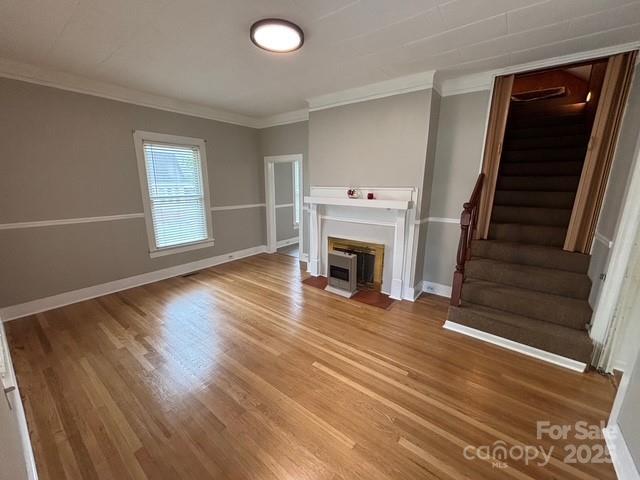 103 Duke St, Great Falls, SC 29055 - unfurnished living room with stairs, a fireplace with flush hearth, wood finished floors, ornamental molding, and baseboards