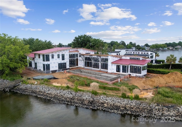 rear view of house featuring a water view, a garden, and metal roof