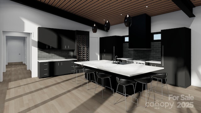 kitchen featuring light countertops, dark cabinets, a sink, tasteful backsplash, and wooden ceiling
