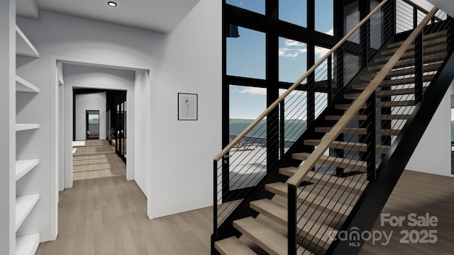 stairway with wood finished floors, healthy amount of natural light, and recessed lighting