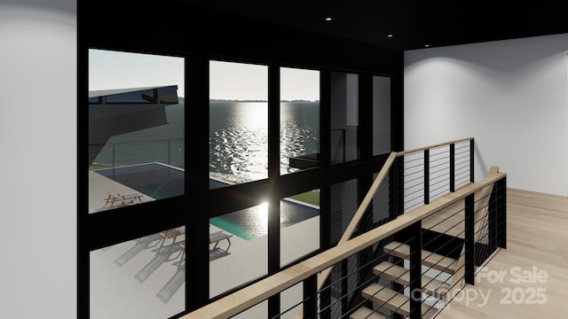 corridor featuring a water view, wood finished floors, and an upstairs landing
