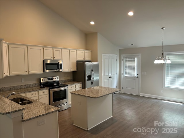 kitchen featuring appliances with stainless steel finishes, high vaulted ceiling, a sink, white cabinetry, and a kitchen island