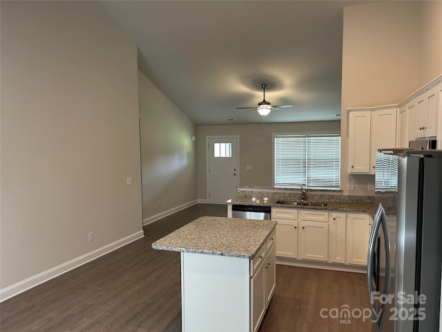 kitchen featuring stainless steel appliances, a sink, dark wood-style flooring, a ceiling fan, and white cabinets