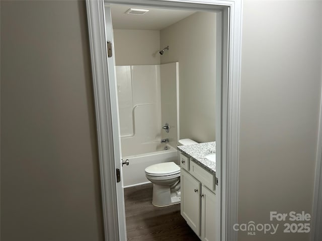 full bath featuring wood finished floors, toilet, vanity, and tub / shower combination