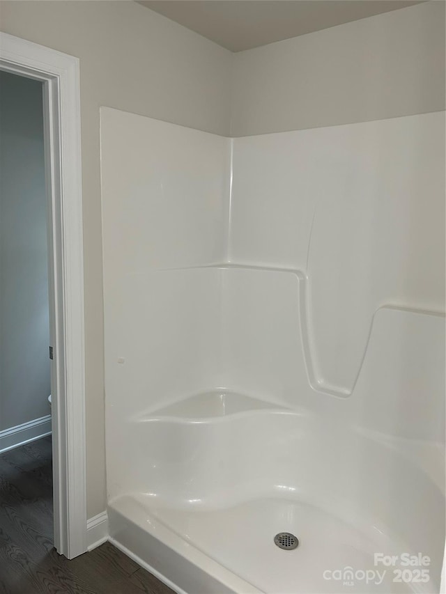 bathroom featuring wood finished floors, baseboards, and a shower