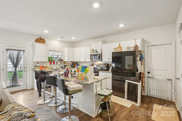 3985 Village Blvd NW, Conover, NC 28613 - kitchen featuring appliances with stainless steel finishes, a kitchen bar, a center island, dark wood-style floors, and white cabinets