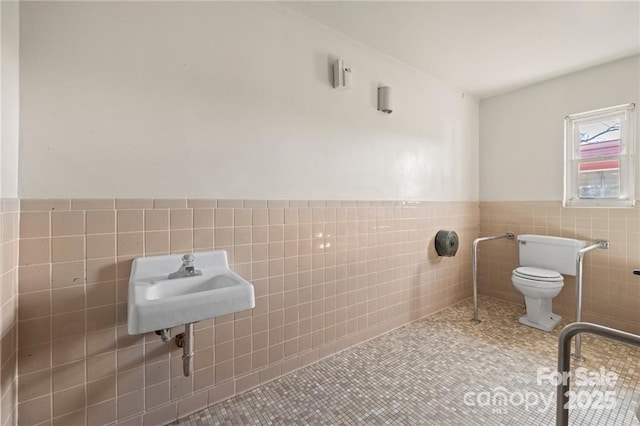 324 Horn Bottom Rd, Forest City, NC 28043 - bathroom featuring tile walls, toilet, a wainscoted wall, tile patterned flooring, and a sink