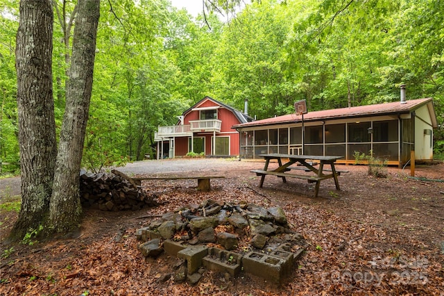 144 Wishing Stone Ln, Sylva, NC 28779 - back of property featuring a sunroom, an outdoor fire pit, a chimney, a wooded view, and metal roof