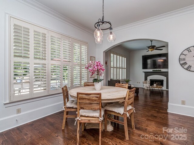 1404 Lookout Cir, Waxhaw, NC 28173 - dining area with arched walkways, ceiling fan, a fireplace, wood finished floors, and ornamental molding