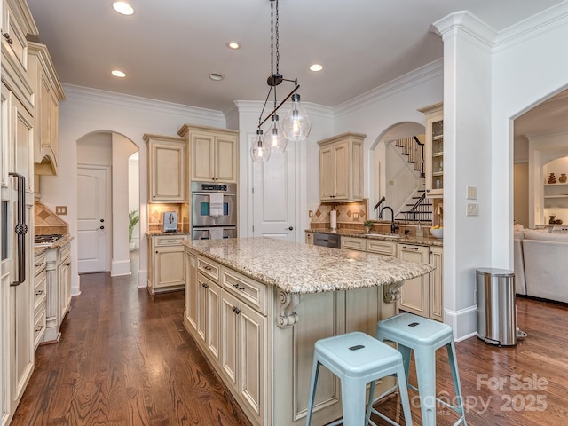 1404 Lookout Cir, Waxhaw, NC 28173 - kitchen featuring cream cabinets, arched walkways, a sink, a kitchen island, and stainless steel double oven