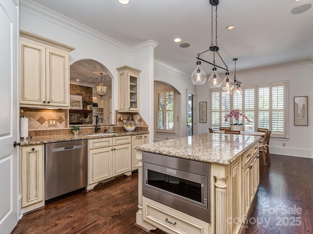 1404 Lookout Cir, Waxhaw, NC 28173 - kitchen featuring cream cabinetry, stainless steel appliances, arched walkways, a sink, and backsplash