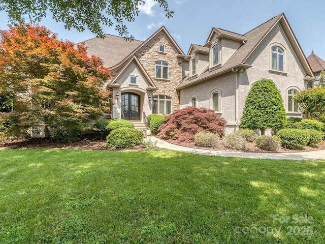 1404 Lookout Cir, Waxhaw, NC 28173 - french country home with a front yard, stucco siding, stone siding, and roof with shingles