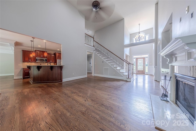 4113 Hoffmeister Dr, Waxhaw, NC 28173 - unfurnished living room featuring a towering ceiling, dark wood-style flooring, a ceiling fan, and baseboards