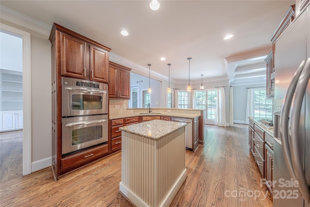 4113 Hoffmeister Dr, Waxhaw, NC 28173 - kitchen with appliances with stainless steel finishes, a peninsula, a sink, light stone countertops, and light wood-type flooring