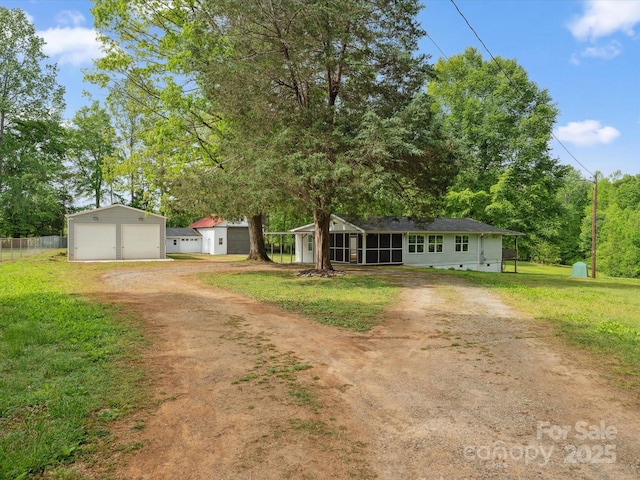 view of front facade with an outbuilding, driveway, a detached garage, and a sunroom