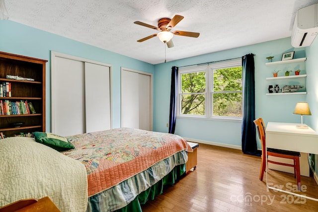 6334 Jacks Creek Rd, Burnsville, NC 28714 - bedroom with a wall mounted AC, two closets, wood finished floors, baseboards, and a textured ceiling