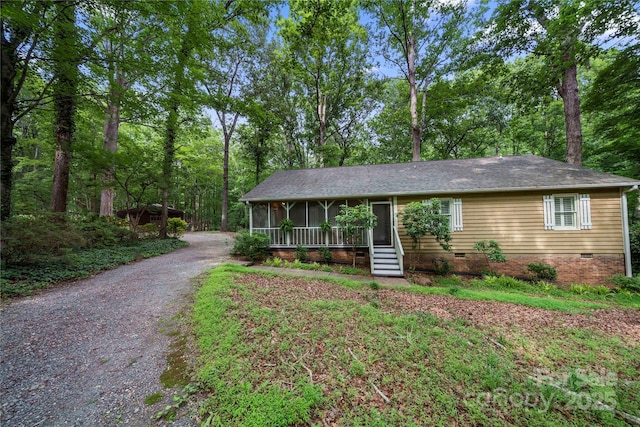 single story home featuring crawl space, a sunroom, roof with shingles, and gravel driveway