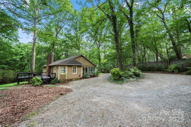 view of front of property featuring fence, a chimney, a wooden deck, and driveway