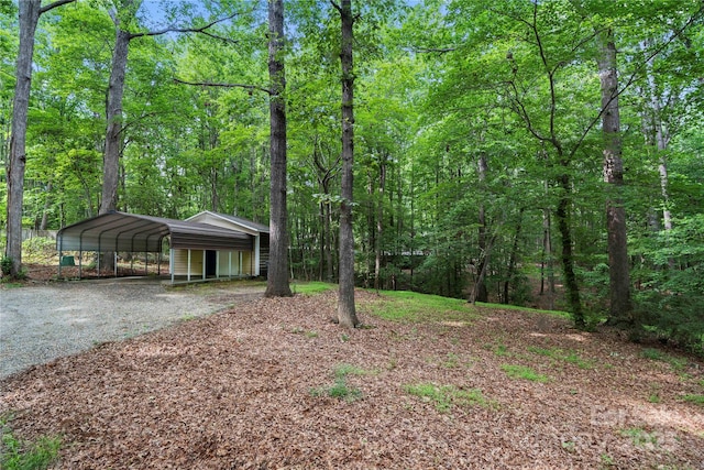 view of front of property featuring driveway, a carport, and a forest view