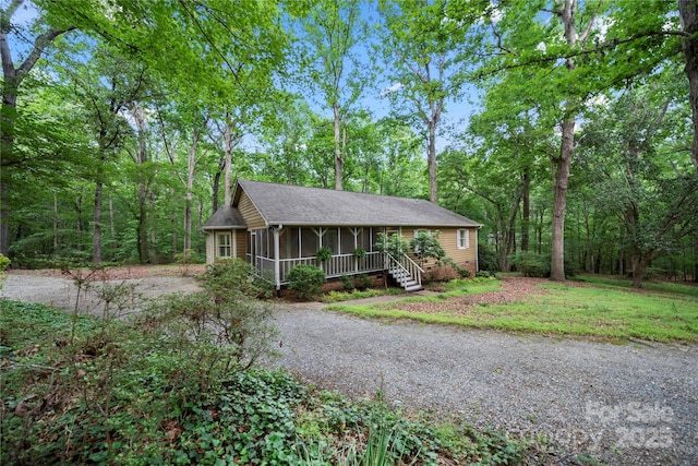 ranch-style home featuring a sunroom, driveway, and a shingled roof