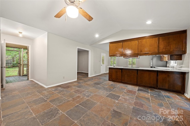 kitchen with stone tile flooring, baseboards, plenty of natural light, ceiling fan, and lofted ceiling